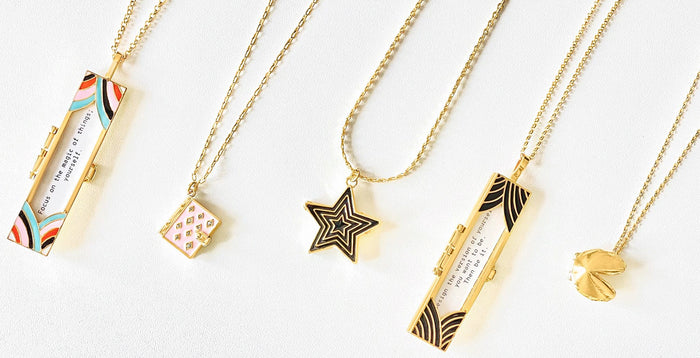 Deco Fortune Locket (Multi-Color), Stardust Book Locket (Blush), Deco Star Locket (Onyx), Deco Fortune Locket (Onyx), and Fortune Cookie Locket (Gold) all lined up.